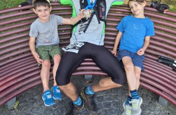 Tommi con la medaglia della BRAVE 38K seduto su una panchina insieme ai figli dopo il Trail Lago Maggiore