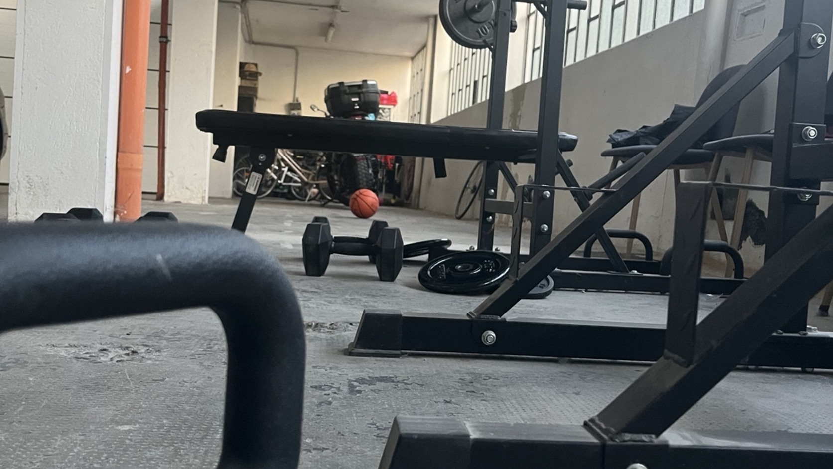 Kettlebell, panca e bilanciere nella palestra domestica Vault 101 di Tommi